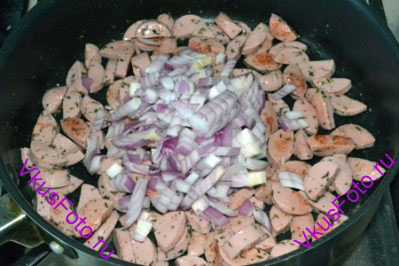 К сосискам добавить лук и продолжить жарить под крышкой 10 минут.