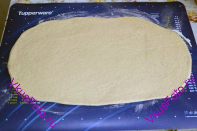 Когда тесто поднимется, выложить его на доску и раскатать скалкой толщиной примерно 2 см.