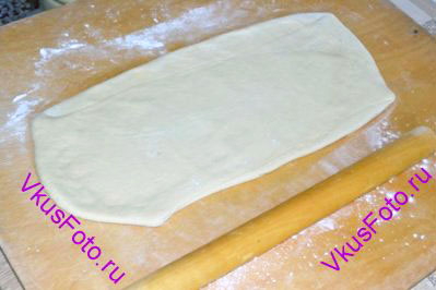 Раскатать тесто в прямоугольник с длиной примерно 60-70 см. Работать скалкой нужно только в продольном направлении, при этом скалку нужно держать за концы, чтобы давление на тесто было равномерным.