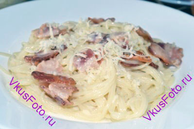 Разложить спагетти карбонара по тарелкам вместе с соусом. Сверху посыпать тертым сыром. 
