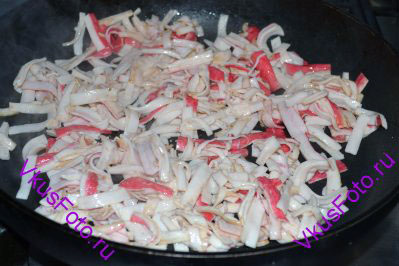 В сковороде, где жарились грибы, обжарить крабовые палочки с добавление растительного масла. Крабовые палочки во время жарки быстро прилипают к сковороде, поэтому их нужно постоянно помешивать. Жарить около 5 минут. Крабовые палочки вынуть.