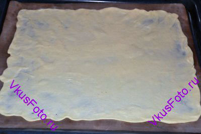 Раскатать тесто в очень тонкий пласт. Чтобы легче было раскатывать скалку можно протереть оливковым маслом. Положить первый пласт теста на противень с пекарской бумагой.