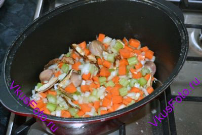В кастрюлю с толстым дном влить немного масла, поместить все овощи, добавить грибы и лавровый лист. Обжаривать на плите, помешивая, в течении 5 минут.